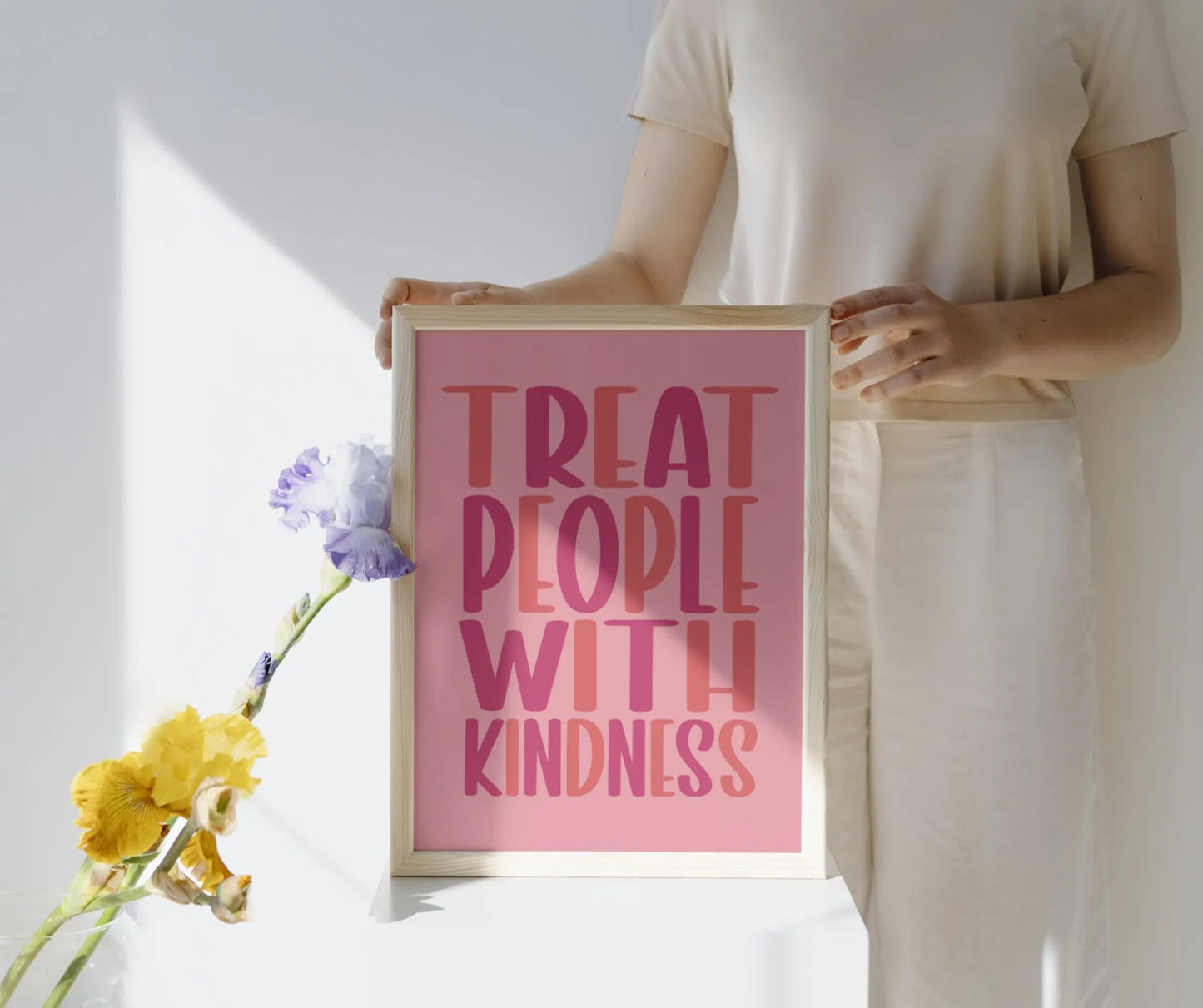 “Treat People with Kindness” Quote Print in shades of pink lettering with a lighter pink background. Available in A4-A2 sizes. The image shows a mockup of the print in a natural-effect frame.