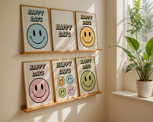 A series of 'Happy Days' retro art prints with various colored smiley faces displayed on a wall, below a window with natural light coming in and a plant to the side.