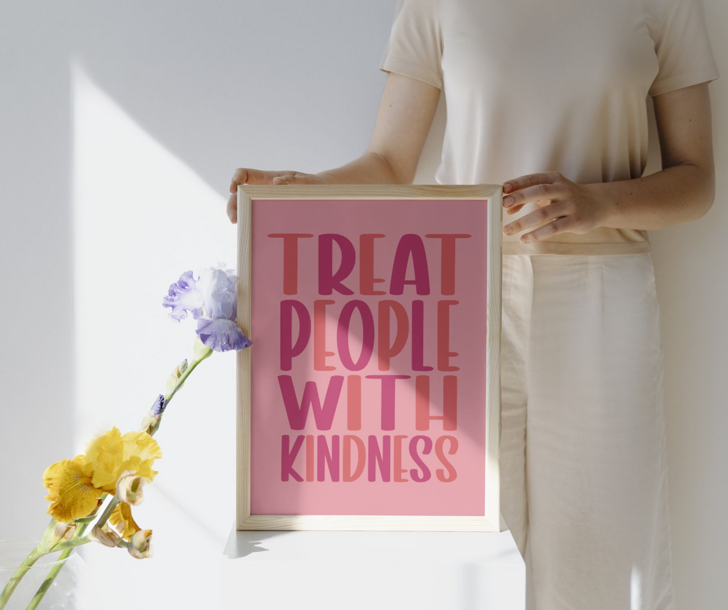 “Treat People with Kindness” Quote Print in shades of pink lettering with a lighter pink background. Available in A4-A2 sizes. The image shows a mockup of the print in a natural-effect frame. 